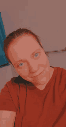 a woman with blue eyes and a red shirt is smiling