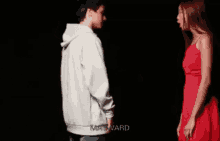 a man in a white hoodie is pointing at a woman in a red dress ..
