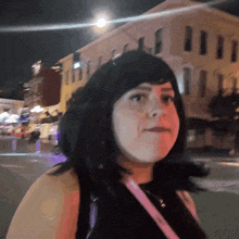 a woman wearing a black top and a pink purse stands in front of a building