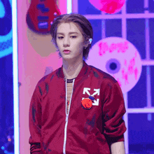 a young man wearing a red jacket with a white arrow on the front