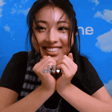 a woman making a heart with her hands and a blue background with the word ne on it