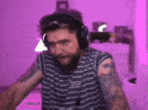 a man wearing headphones and a striped shirt has a tattoo on his arm that says mihai48