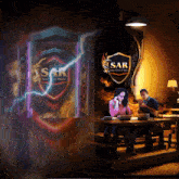 a man and a woman are sitting at a table in front of a sign that says sar
