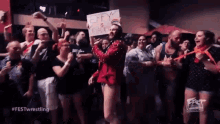 a man in a red jacket is standing in front of a crowd of people holding a sign that says jeffy is back .