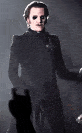 a man in a black suit is standing on a stage in front of a microphone .