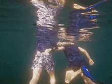 two people are swimming underwater with a reflection of their bodies in the water