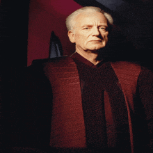 a man with gray hair and a red jacket with a pattern on it