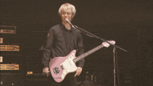 a man playing a pink guitar in front of a marshall amp