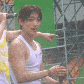 a man in a white tank top is holding a microphone and pointing at someone .