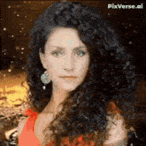 a woman with long curly hair is wearing earrings and a red dress