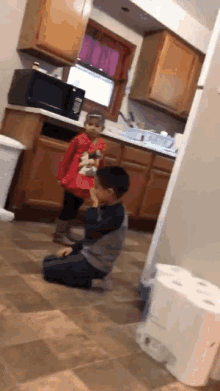 a boy and a girl are playing in a kitchen