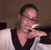 a woman with glasses is brushing her teeth with a toothbrush