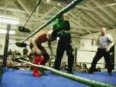 two men are wrestling in a wrestling ring with a referee watching