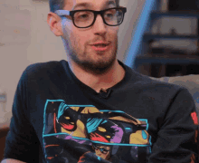 a man wearing glasses and a black shirt with a picture of batman