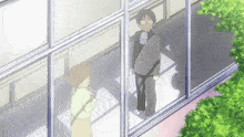 a man and woman are standing in front of a window