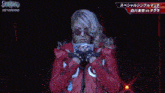 a woman wearing sunglasses and a red jacket is standing on a stage .