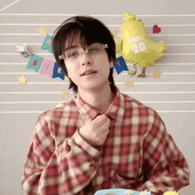 a man wearing glasses and a plaid shirt is standing in front of a balloon that says " toki 20 "