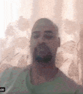 a man with a beard is sitting in front of a window with a clock that says 2:00 on it