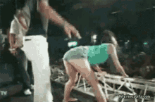 a woman in shorts is dancing on a stage with a man behind her .