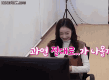 a woman sitting in front of a computer screen with korean writing on the screen