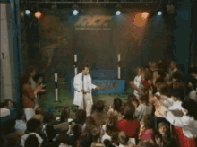 a man in a white shirt is dancing in front of a crowd with a sign that says nc on it