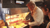 a man in a suit is standing in front of a display of french fries and ketchup