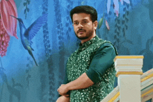 a man in a green shirt is standing on a set of stairs in front of a mural