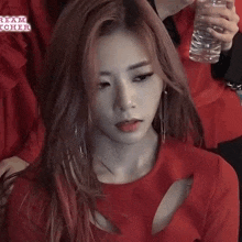 a woman in a red dress is holding a glass of water .
