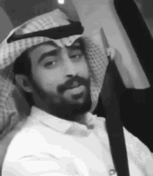 a black and white photo of a man with a beard wearing a turban and a white shirt .