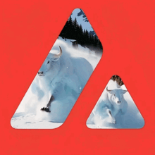 a picture of a bull running in the snow with a mountain in the background