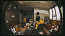 a man in a yellow hoodie sits on a red couch