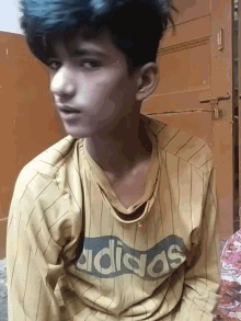 a young man wearing an adidas shirt looks down