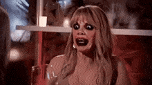 a woman is making a funny face while holding a glass of wine in a dark room .
