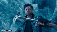 a man in a leather jacket is holding a hammer in front of a blue background