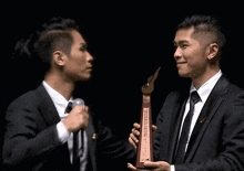 a man in a suit holds a trophy that says ' a ' on it