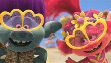 two trolls wearing heart shaped sunglasses on the beach .