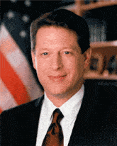 a man in a suit and tie stands in front of a flag