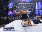 two women are wrestling in a ring with a sign that says replay on it