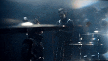 a man is playing a drum set in a dark room