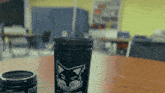 a black cup with a cat on it is on a table