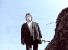a man in a suit and gloves is standing on top of a pile of hay .
