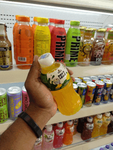a person is holding up a bottle of orange juice with the word prime on the front