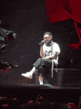 a man in a white shirt is singing into a microphone on a stage in front of a crowd