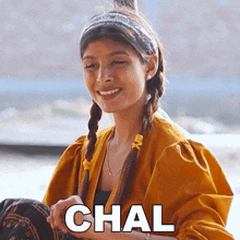 a woman wearing a yellow jacket and a headband is smiling with the word chal above her