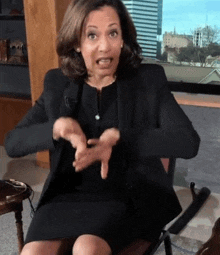 a woman in a black suit is sitting in a chair