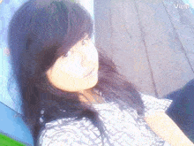a girl with long black hair is sitting on a wooden bench with the name victi written in the corner