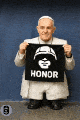 a statue of pope francis holding a black banner that says honor
