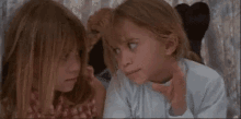 two little girls are laying next to each other on a bed .