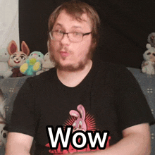a man wearing glasses and a black shirt that says wow on it