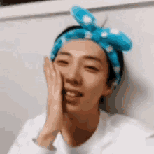 a close up of a person wearing a blue headband covering their face with their hands .